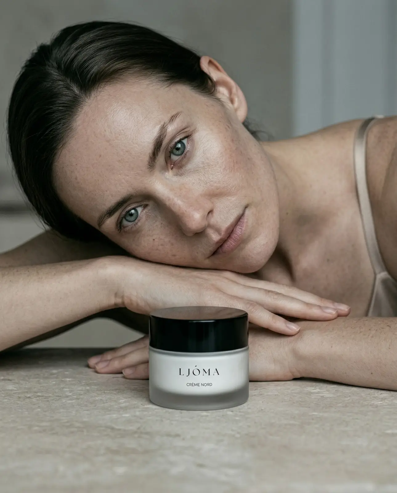 Woman resting her head on her arms beside a frosted Ljóma Crème Nord jar